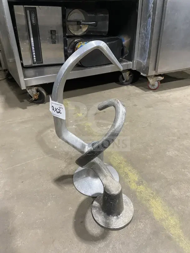 Commercial stainless steel spiral dough hooks in used condition, sturdy design, auction tag visible.