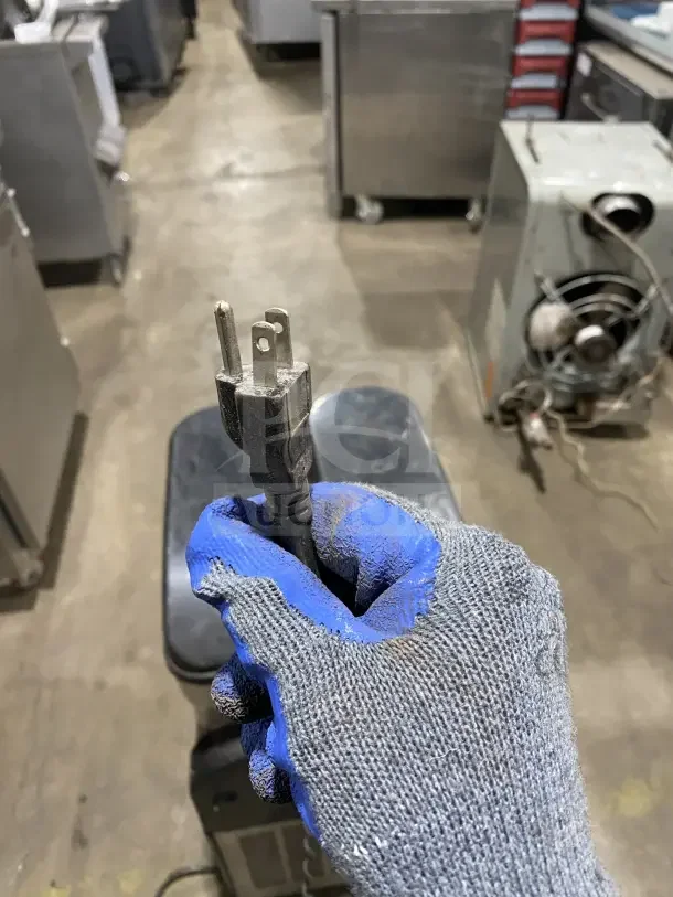 Omega OFS20 Slushie Dispenser power plug held by gloved hand. 120V, single-phase. Model: OFS20, SN: 2FS16100006.