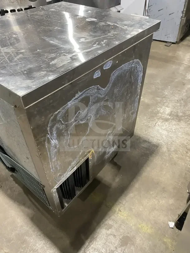 Leader stainless steel single-door undercounter refrigerator on casters, visible wear on surface, includes poly-coated wire rack.