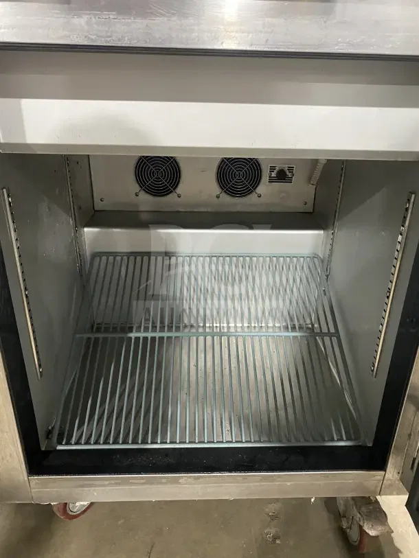 Leader commercial stainless steel single-door undercounter refrigerator with poly-coated wire rack, on casters, interior view.