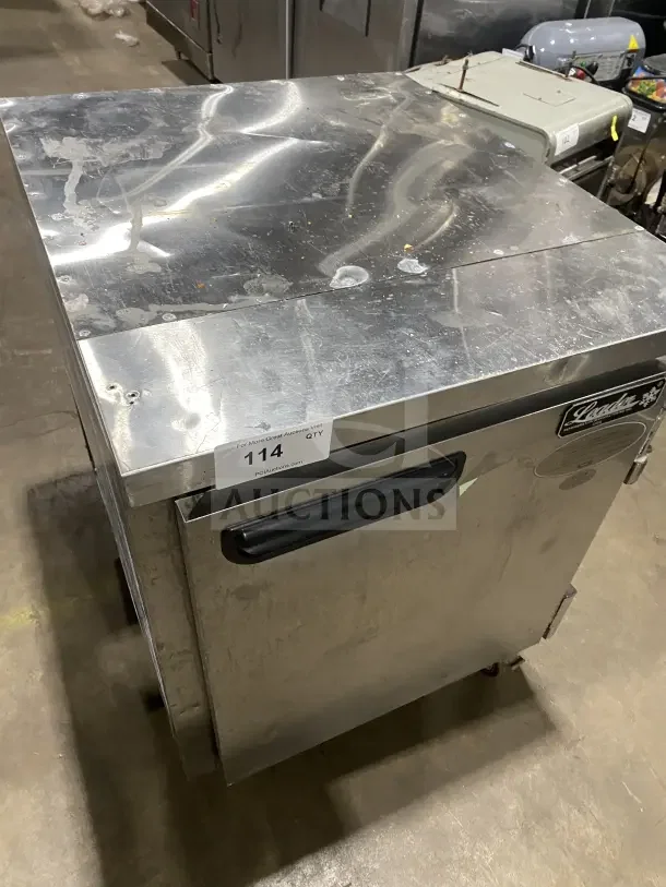 Leader Commercial stainless steel undercounter refrigerator, single-door, poly-coated wire rack, on casters, visible wear.