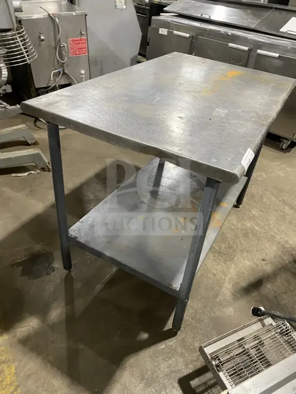 Commercial stainless steel utility stand with two compartments, showing signs of wear. Ideal for kitchen use.