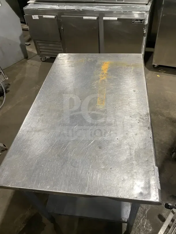 Commercial stainless steel utility stand with two compartments, showing signs of wear. Suitable for kitchen use.