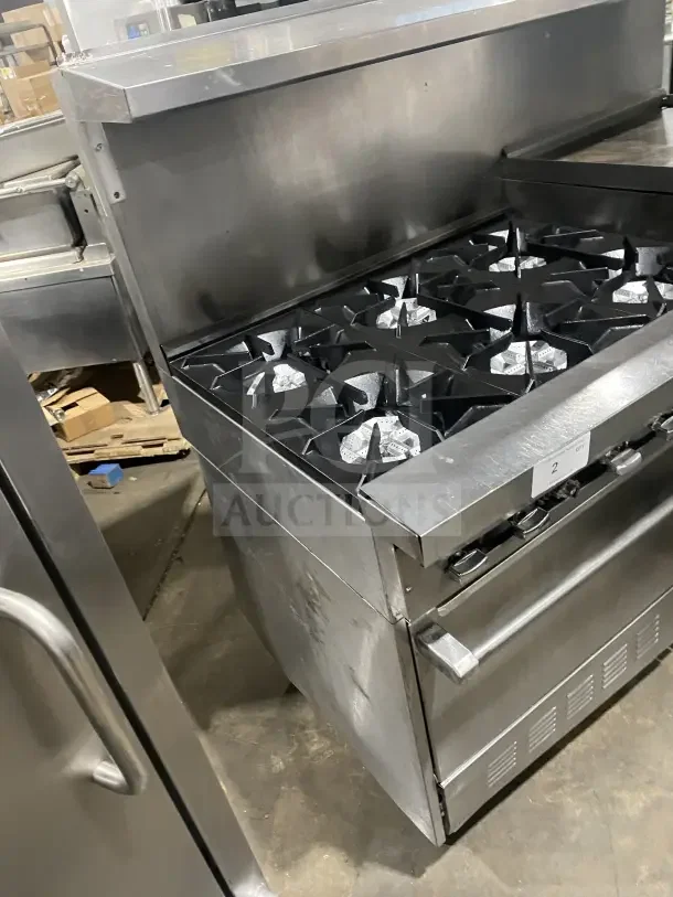 Sunfire commercial stainless steel gas range with 6 burners, side griddle, 2 ovens, and oven wire rack on casters.