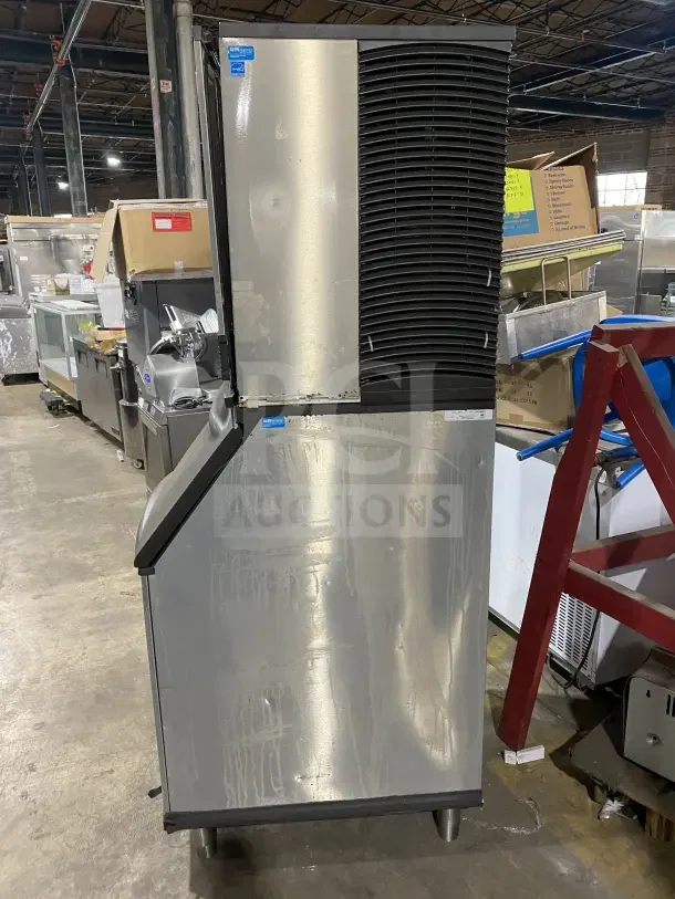 Manitowoc stainless steel ice machine IY1106A-261, electric, air-cooled, in good condition, on legs, with bins visible.