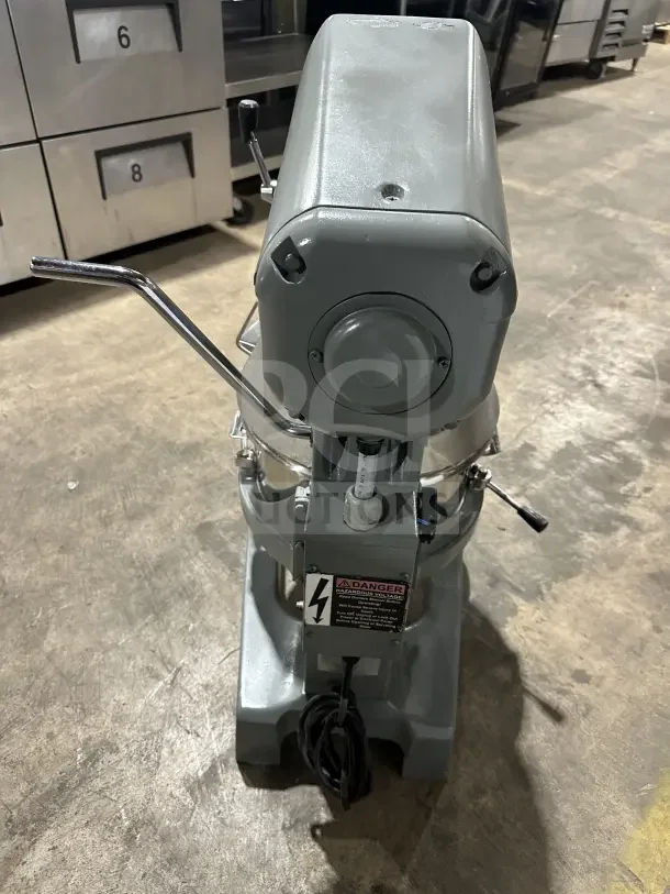 Globe commercial countertop heavy-duty planetary mixer with stainless steel bowl and guard, visible voltage warning label.