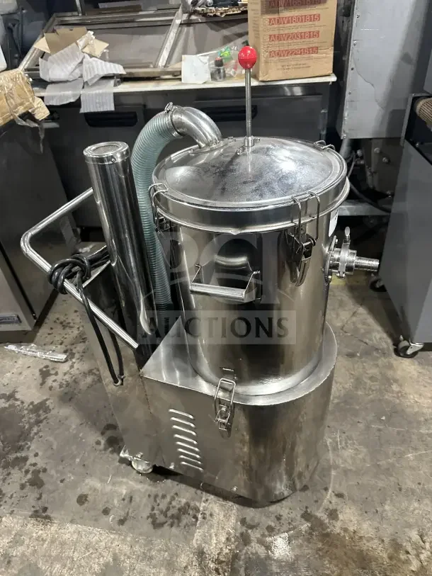 Industrial stainless steel mixer, featuring a secure lid with a red handle, attached hose, and mounted on wheels for mobility.