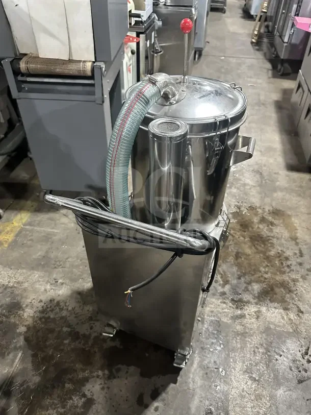 Industrial stainless steel machine with hose and red-topped lever, on wheels. Visible wires and side handles. Used condition.