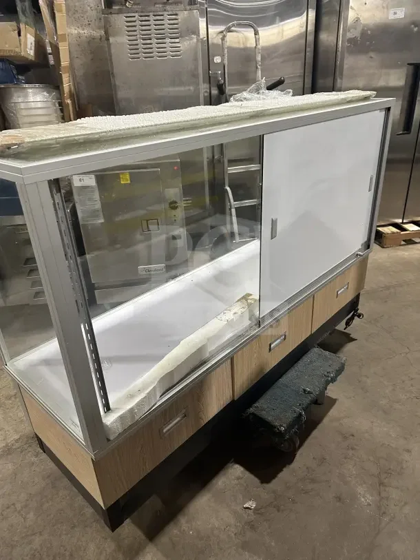 Commercial glass display case with wood base, sliding doors, and visible storage. Good condition, suitable for retail use.
