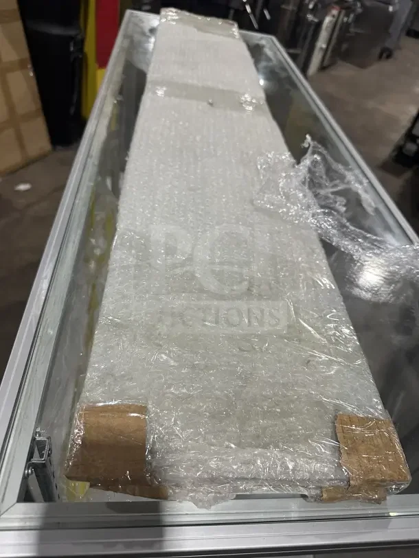 Commercial Extra-Vision retail glass display case with wood base accent, shown wrapped in bubble wrap. Condition appears new.