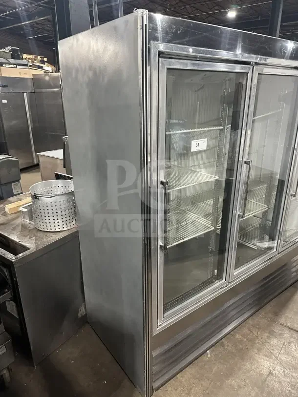Commercial stainless steel 3-door sliding glass refrigerator merchandiser with poly-coated wire racks, in gently used condition.