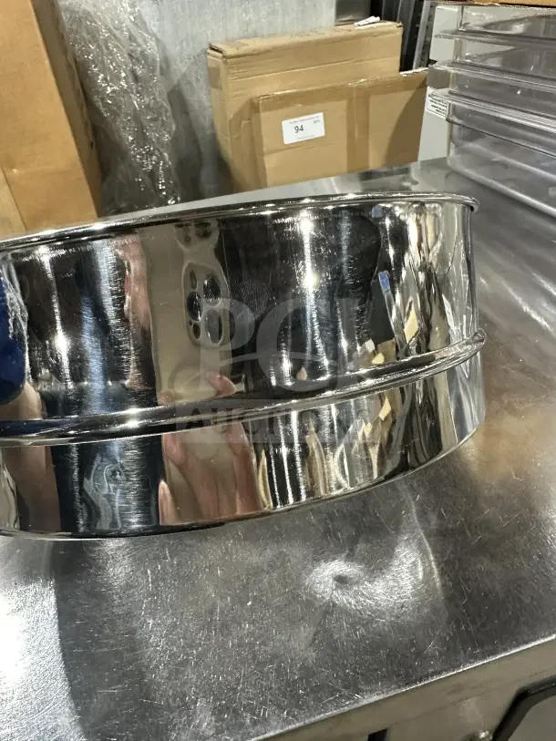 Brand new commercial stainless steel flour sieve with fine mesh, reflective finish, pristine condition; enhances baking precision.