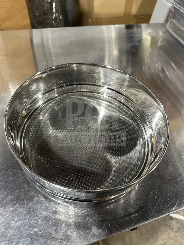 Brand new commercial stainless steel flour sieve with fine mesh, reflecting light on a metallic surface, excellent condition.