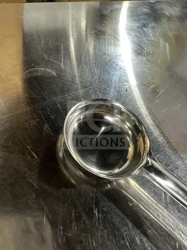 Brand new 2 oz stainless steel portion control spoon on reflective surface, ideal for commercial use.