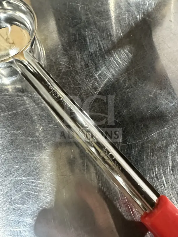 Brand new stainless steel 2 oz solid portion control spoon with red handle, perfect for commercial use.