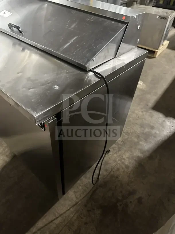 True commercial stainless steel 2-door refrigerated prep table, electric powered, sturdy build, visible power cord.