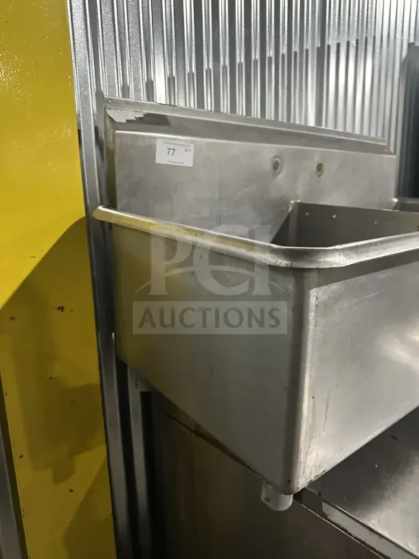Commercial stainless steel 2-compartment scullery sink with legs. Durable, industrial-grade, with visible wear. Label “77.”
