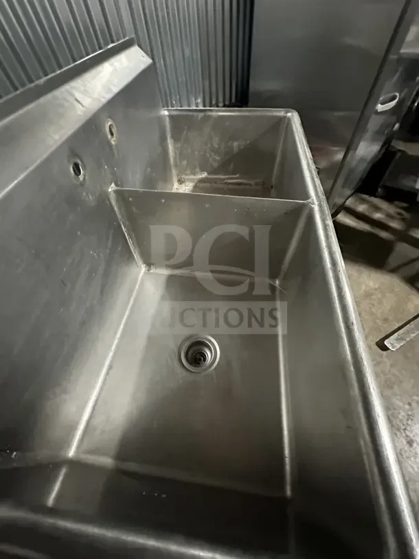 Commercial stainless steel 2-compartment scullery sink with legs, slightly worn, ideal for utility areas.