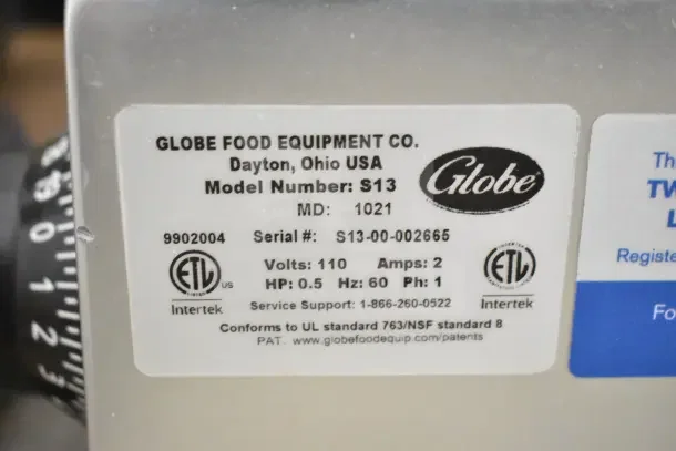 2021 Globe S13 Commercial Meat Slicer with blade sharpener. Model S13, 110V, 1 Phase. Tag shows serial and model info.