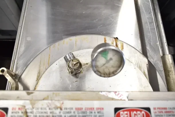 Broaster 1800 gas pressure fryer showing temperature gauge, stainless steel body, signs of wear, warning labels visible.