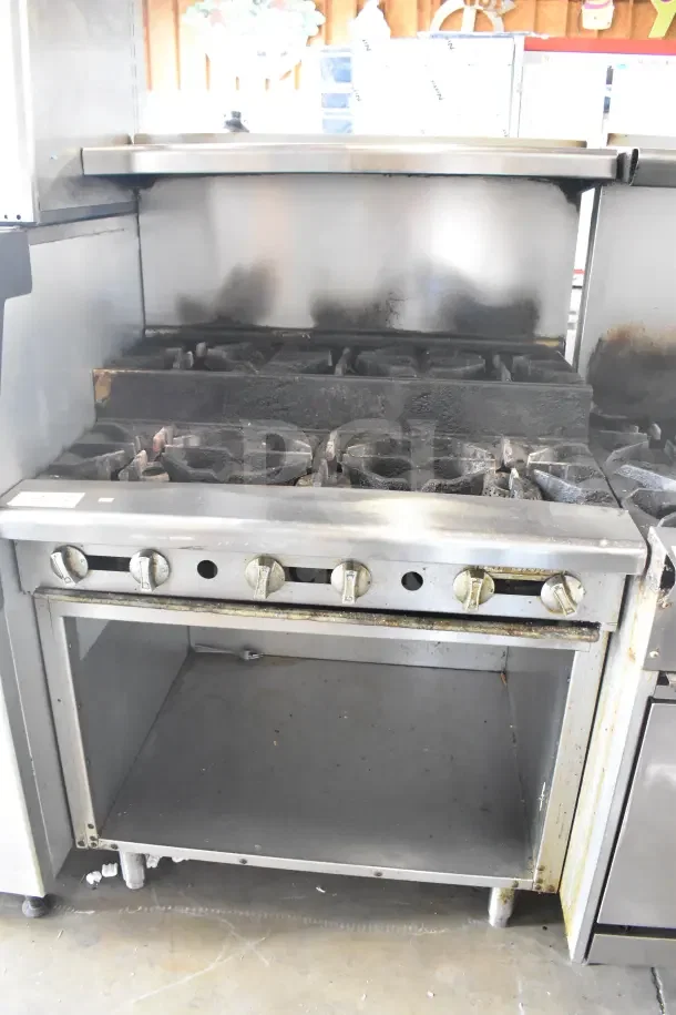Commercial gas-powered 6-burner range with 2 tiers, overhead shelf, back splash, and under shelf; used condition.