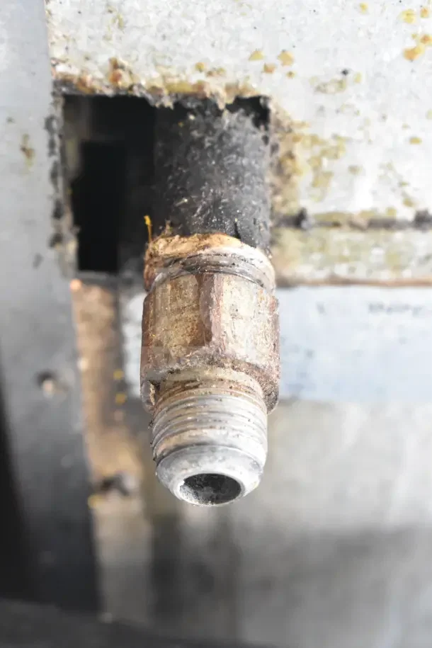 Rusted gas connection on a commercial 6-burner stove, showing wear and signs of corrosion.