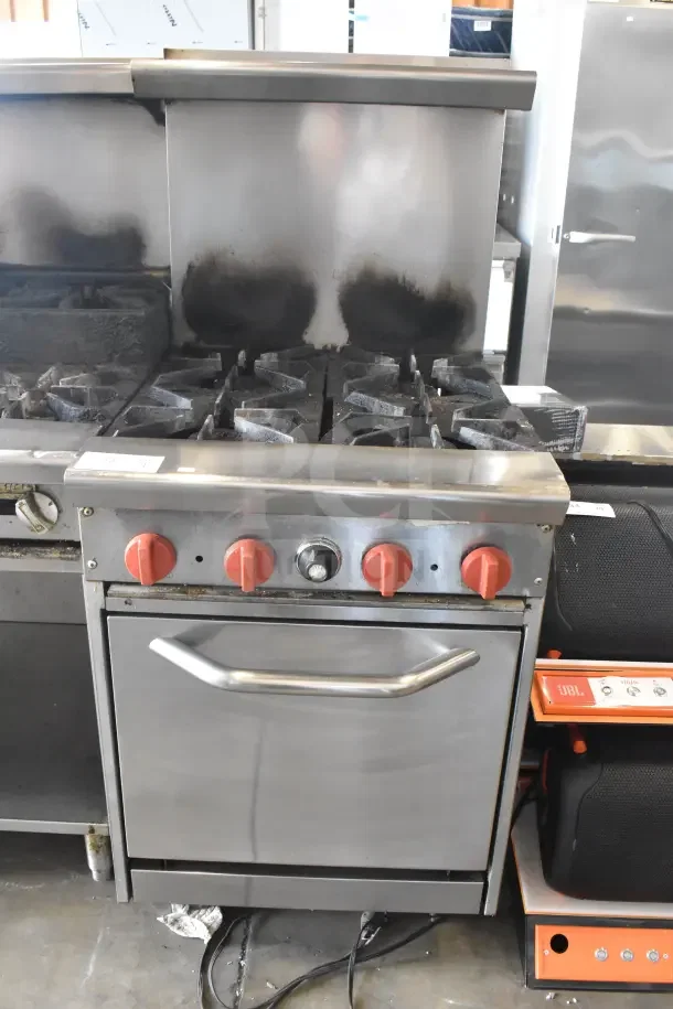 Standex 24GFGV4B20N 4-burner range with oven, over shelf, and backsplash. Natural gas, used condition, red knobs.