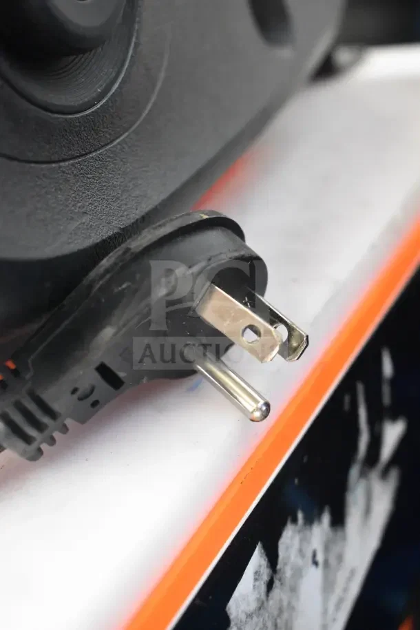 Close-up of a power plug attached to a JBL Partybox 110 portable Bluetooth speaker on a store display.