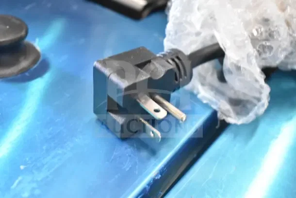 Close-up of the plug for a 2025 Avantco 177F202 dual tank electric fryer, showing a three-prong design on a metal surface.