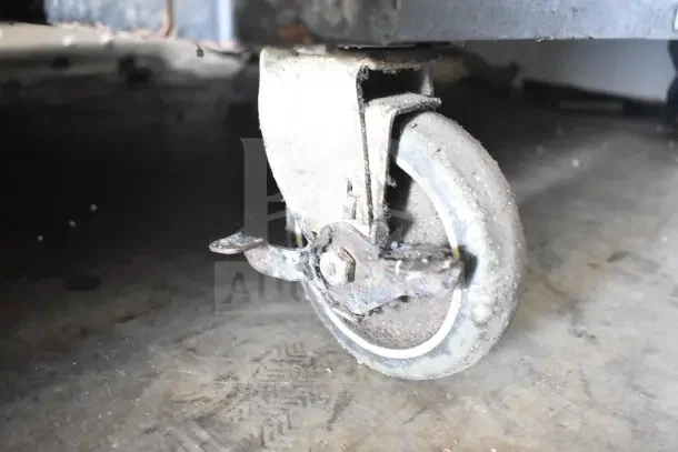 Lakeside Commercial Bakery Transport Rack with worn metal caster shown, featuring brake mechanism. Used condition.