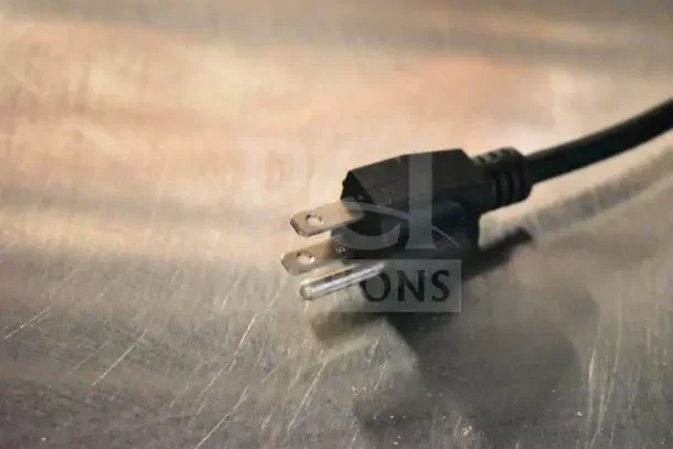 A black electrical plug on a metallic surface, part of a Lakeside commercial bakery transport rack.