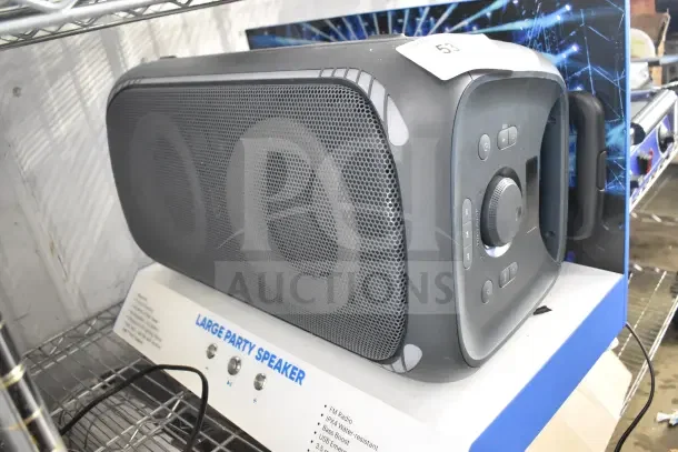 Onn Large Party Speaker store display, black with control panel. Key features: FM Radio, IPX4 water-resistant, bass boost, 3.5 mm aux.