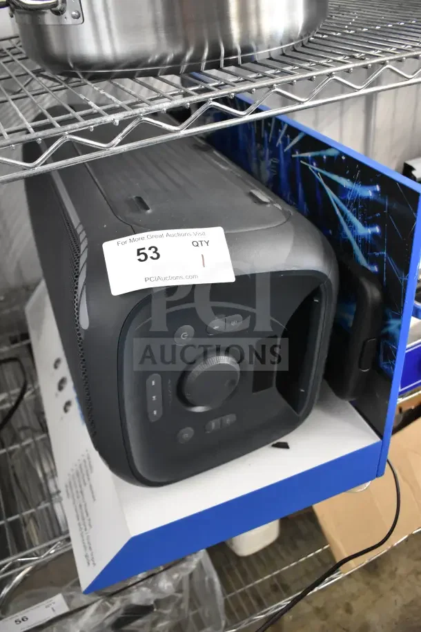Onn Large Party Speaker display model on metal rack. Features control panel, large dial, and sturdy handle. Auction tag visible.