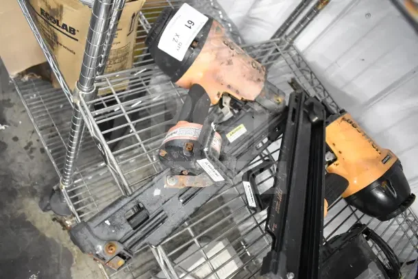 Two Bostitch F33PT framing nailers, worn condition, visible rust marks and labels, stored on metal shelving.