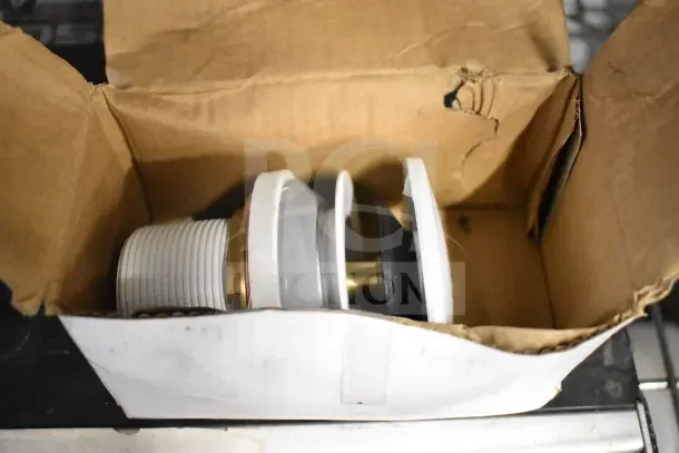 Cardboard box containing white and gray hardware fitting with brass detailing. Box corner slightly damaged.