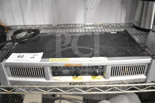 QSC GX5 Power Amplifier on a shelf, showing wear. Labels: "AMP 2 BACK", "C1/C2", "D1/D2." Auction lot 62, V4.
