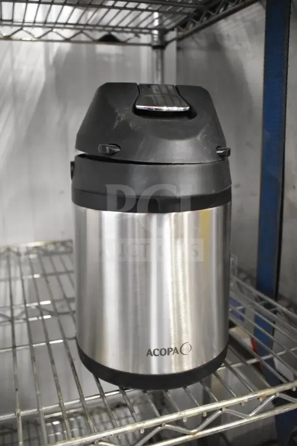 Stainless steel Acopa Air Pot with black lid, in good condition, on metal shelving. Brand logo visible on the side.