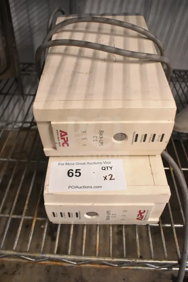 Two APC Back UPS CS 350 units, stacked, with visible labels. Auction tag shows quantity "x2."