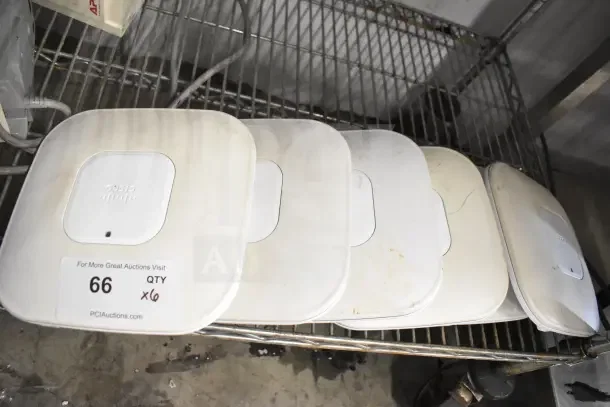 Six Cisco AIR-CAP3502I-A-K9 dual band access points on a metal shelf, showing signs of wear.