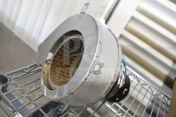 Metal motor unit with integrated fan, model 21TG2KR0V22. Slight wear visible, resting on metal shelf.