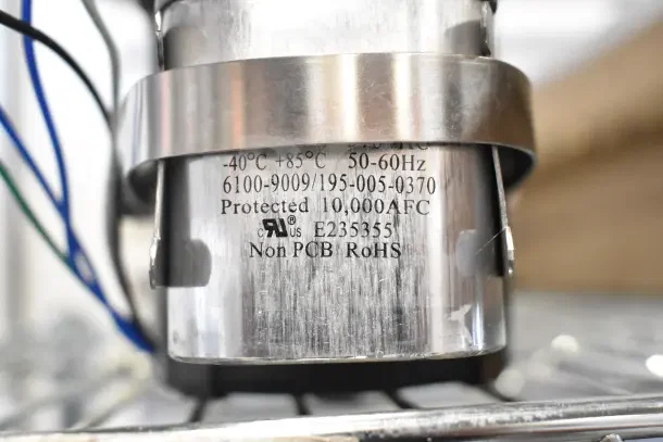 Motor unit with 21TG2KR0V22 marking, metal casing, specs include -40°C to +85°C, 50-60Hz, RoHS compliant.