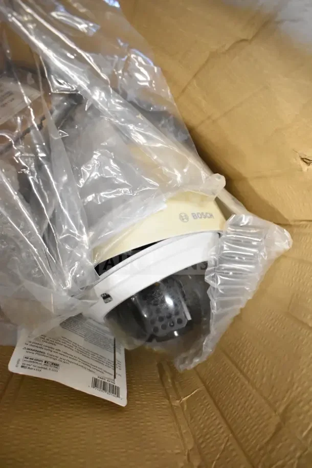Box of Bosch security camera dome in plastic, partially visible in an open cardboard box. Packaging appears intact.