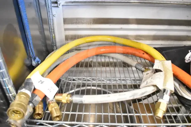 Four assorted hoses in yellow, orange, and white, with brass fittings. Tags visible, labeled "76 x4." Hoses appear in good condition.