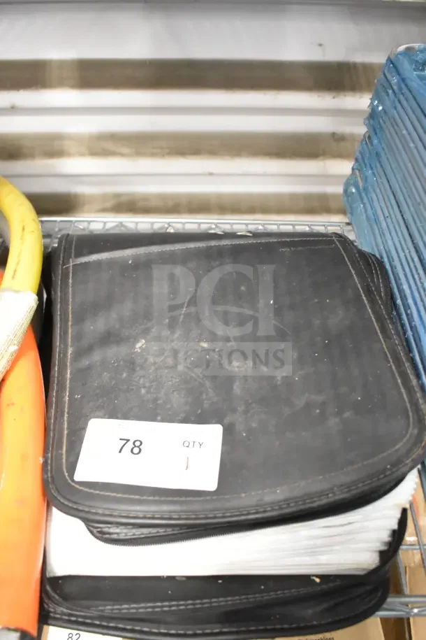 Black CD binder with visible wear, containing pages of CDs. Label marked "78, QTY: 1." Placed on metal shelf.