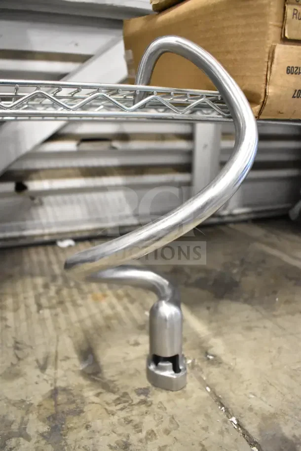 Stainless steel dough hook for mixer, brand new with minor scratches, visible on a metal shelf.