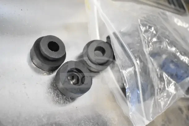 Rubber spacers or seals next to a clear plastic bag, shown on a textured surface.