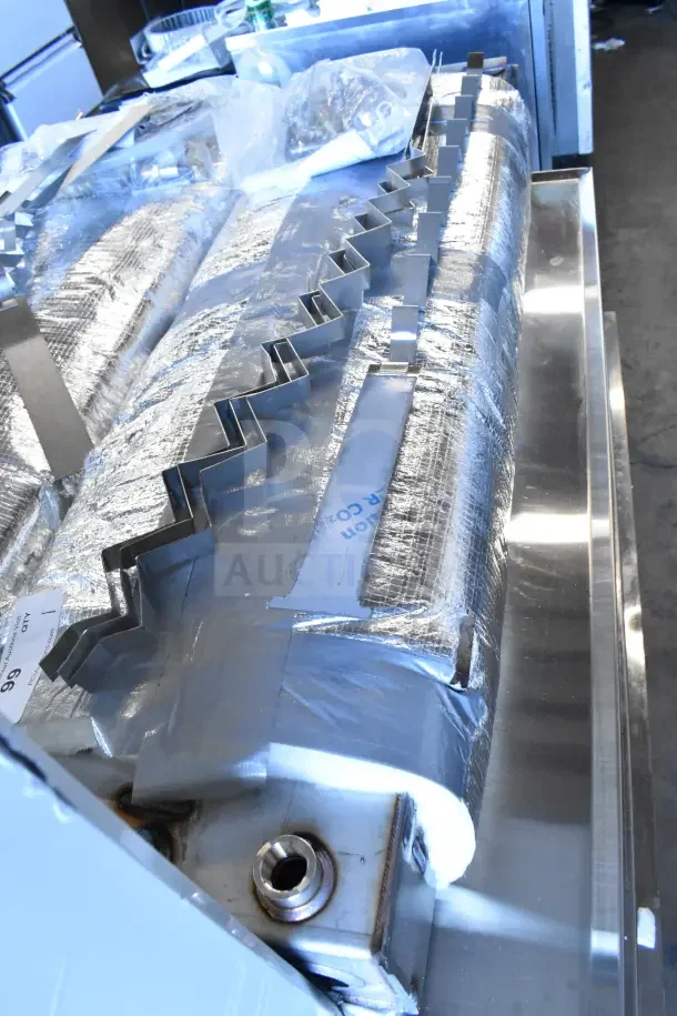 Industrial unit with metallic zigzag components and insulation, reflective surface, and visible connector. Condition appears intact.