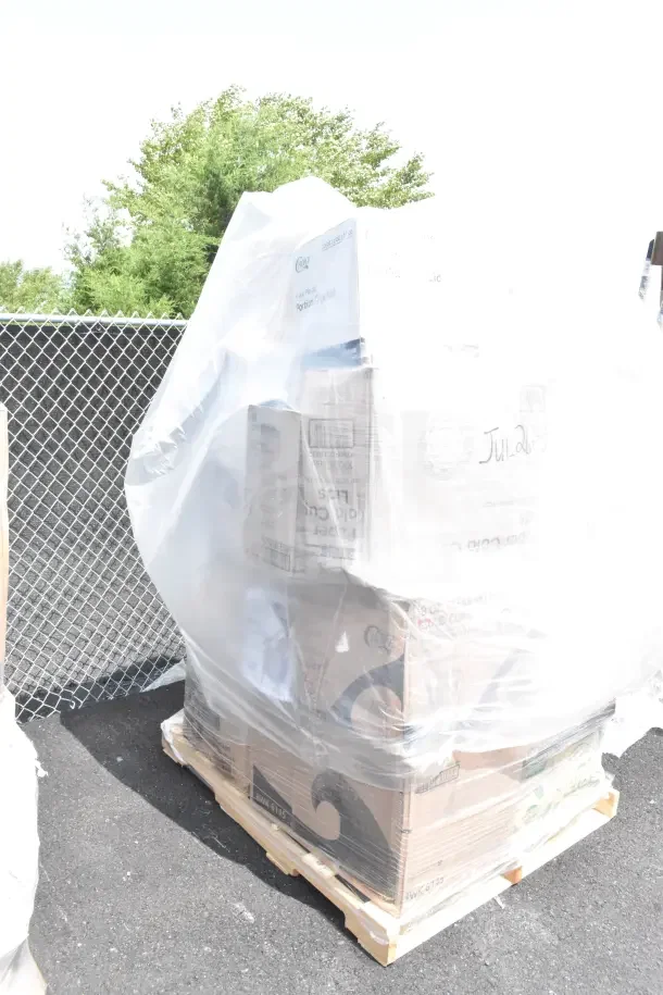 A pallet of 26 brand new scratch and dent items, including lids, cold and hot cups, and plates, wrapped in plastic.