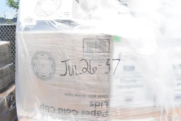 Plastic-wrapped pallet with assorted scratch and dent items including cups and plates. Marked "JUL26-57."