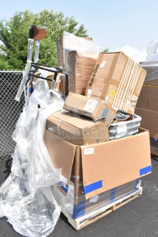 Pile of 28 brand new, scratch and dent items including a chair and hole punch, packaged in boxes on a pallet.